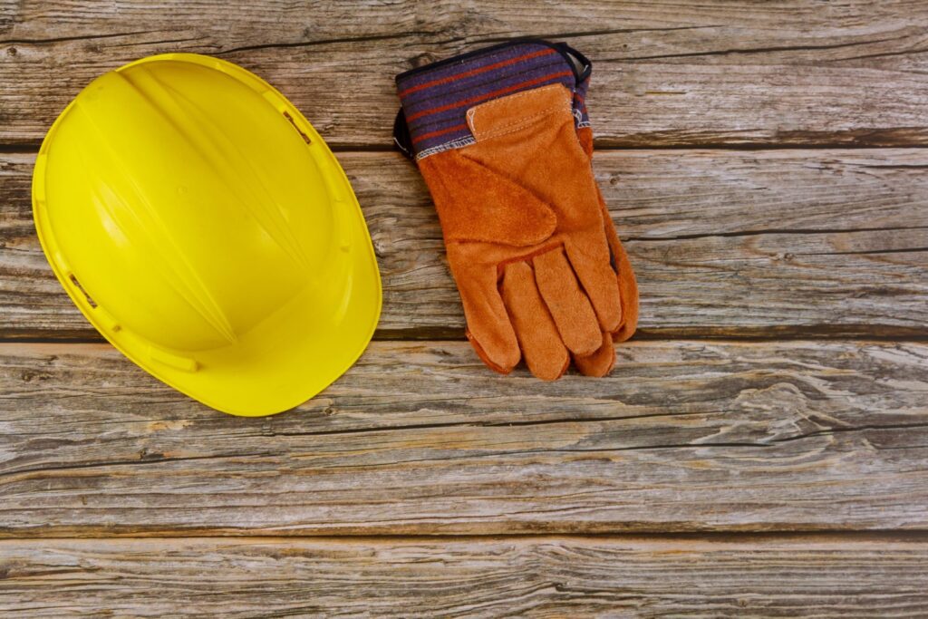 Construction site safety protective hard hat safety gloves on wooden background